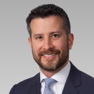 TJ Wilkinson, Attorney at Shulman Rogers wearing a professional suit smiling at the camera posting on a nuetral background